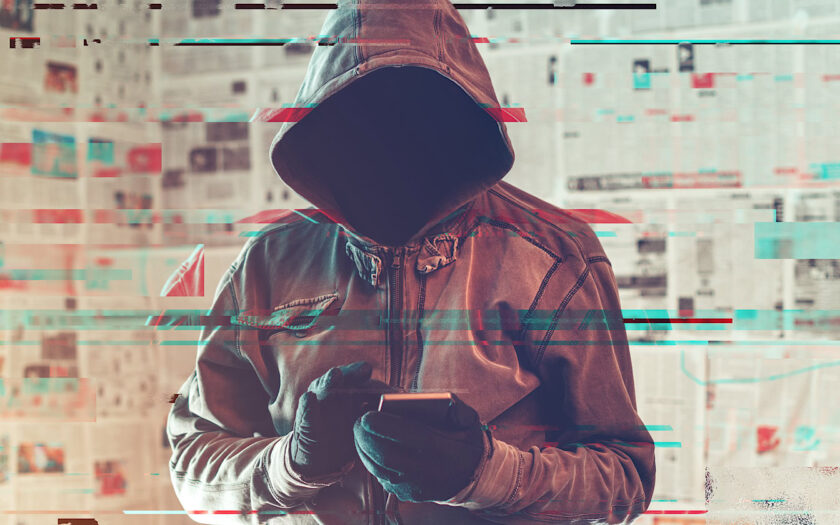 Hooded hacker person using smartphone in infodemic concept with digital glitch effect